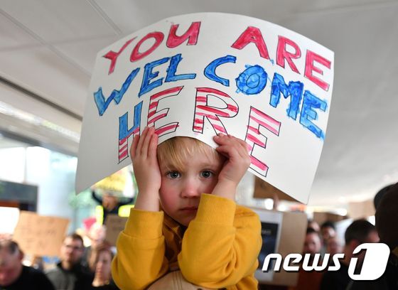 캘리포니아 주 샌프란시스코 국제공항에서 도널드 트럼프 미국 대통령의 반 이민 행정명령에 반대하는 시민의 아이가 “여러분을 환영한다” 플래카드를 들고 집회에 참여하고 있다.  © AFP=뉴스1