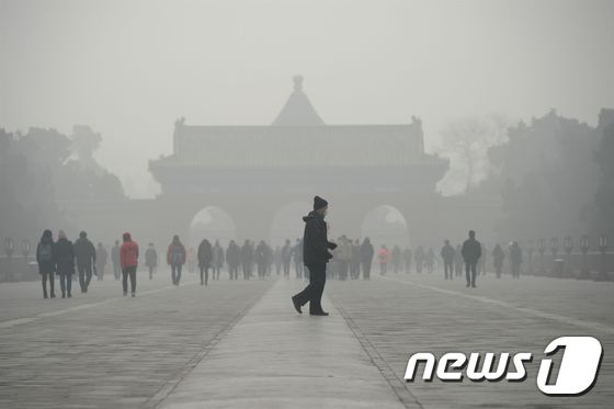 지난달 중국 베이징 천단공원 앞에 짙은 스모그가 깔린 가운데 사람들이 마스크를 쓰고 걸어가고 있다. © AFP=뉴스1