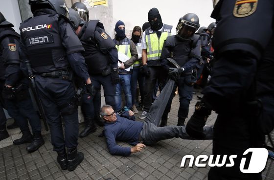스페인 경찰이 1일(현지시간) 카탈루냐 주민들을 분리독립 투표소 바깥으로 끌어내고 있다. © AFP=뉴스1