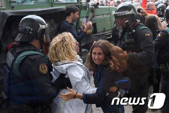 스페인 경찰이 1일(현지시간) 중앙정부와 법원에 의해 위헌으로 규정된 독립투표를 강행한 카탈루냐 자치정부 주민들을 투표소 바깥으로 끌어내고 있다. © AFP=뉴스1