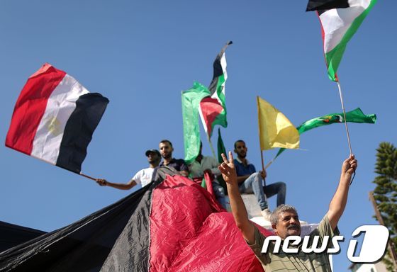 팔레스타인 주민들이 12일(현지시간) 이집트와 팔레스타인·파타·하마스를 상징하는 깃발을 흔들며 통합합의문에 환호하고 있다. © AFP=뉴스1