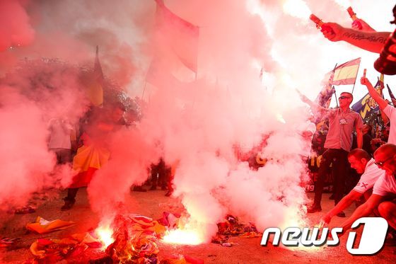 12일(현지시간) 스페인 국경절을 맞아 카탈루냐 주도 바르셀로나에서 분리독립 반대집회 참가자들이 카탈루냐기를 불태우고 있다. © AFP=뉴스1