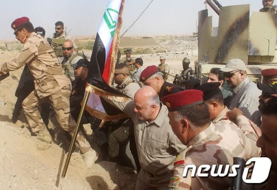 지난 5일(현지시간) 하이데르 알 아바디 이라크 총리가 알카임 탈환 성공하자 국기를 꽂으려는 모습. © AFP=뉴스1