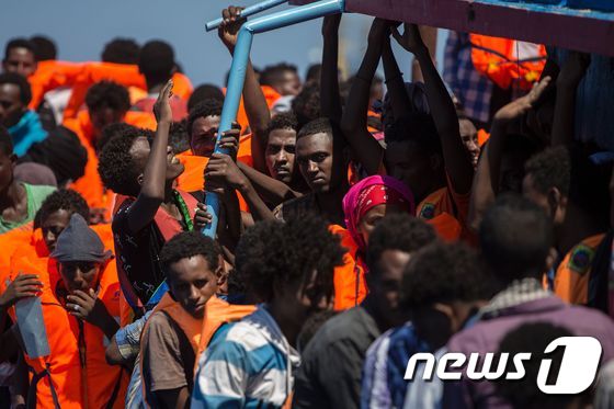 지난 8월 리비아 해안으로부터 작은 배를 타고 지중해를 건넌 아프리카 난민들이 비정부기구(NGO)들에 의해 구조되고 있는 장면. © AFP=뉴스1