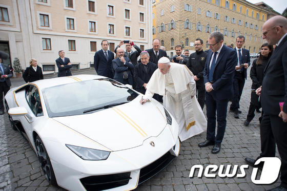 프란치스코 교황이 15일(현지시간) 선물로 받은 람보르기니 슈퍼카 보닛에 사인을 하고있다. © AFP=뉴스1