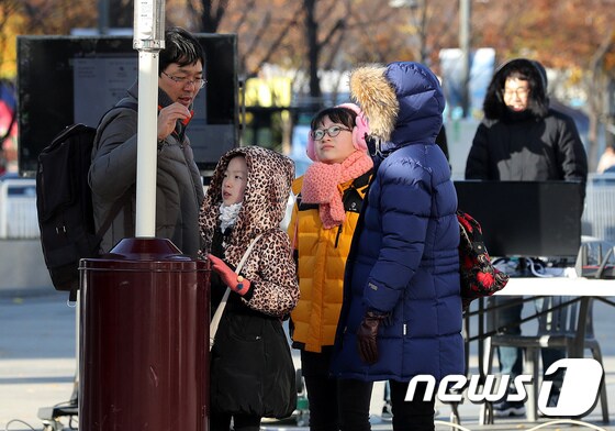 매서운 추위가 몰아친 18일 오후 시민들이 서울 광화문광장에 설치된 난로에서 몸을 녹이고 있다. 2017.11.18/뉴스1 © News1 박지혜 기자