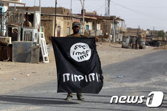 한 이라크 병사가 탈환에 성공한 알카임에서 이슬람국기(IS) 깃발을 흔들며 승리를 자축하고 있다. © AFP=뉴스1