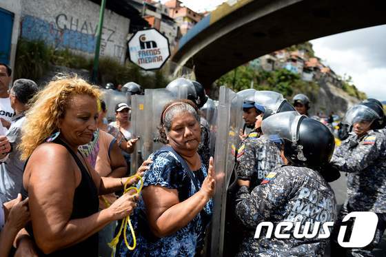 28일(현지시간) 베네수엘라 수도 카라카스에서 식량 부족에 분노한 시민들이 경찰과 대치하고 있다. © AFP=뉴스1