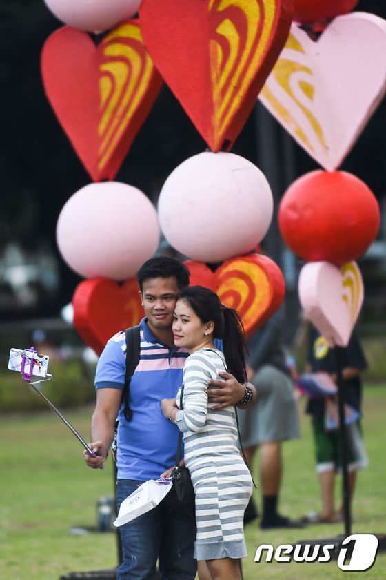 필리핀 마닐라 공원. 발렌타인데이 전날, 공원에 전시된 하트 모양의 장식을 배경으로 인증 사진을 찍고 있는 커플의 모습.© AFP=뉴스1