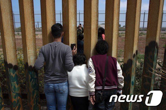 미국과 멕시코 국경지대인 티후아나에서 미 국경순찰대가 멕시코 이민자와 현지 친지들을 위해 가족사진을 찍어주고 있다. © AFP=뉴스1
