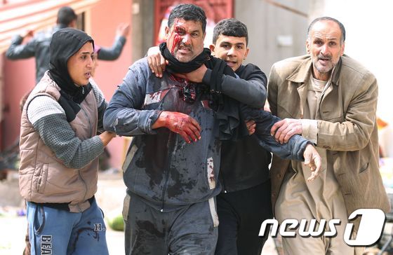 22일(현지시간) 모술의 알 리살라 지역에서 이슬람국가(IS)에 의한 박격포탄에 한 민간인이 다쳐 피를 흘리며 걸어가고 있다. © AFP=뉴스1