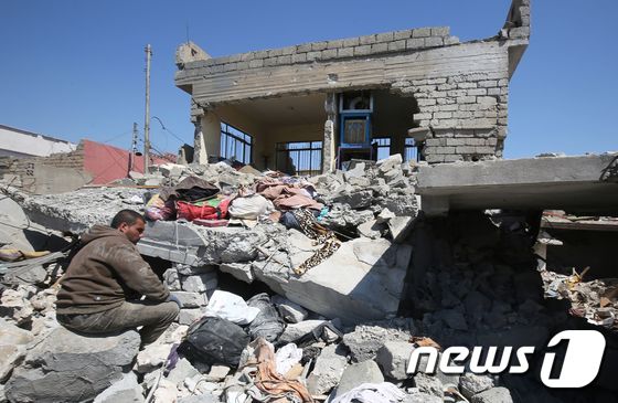 26일(현지시간) 모술 서부 알 자디다 지역에서 한 주민이 미군 주도 연합군의 오폭으로 인해 무너진 건물 잔해 위에서 망연자실한 채 앉아있다. © AFP=뉴스1