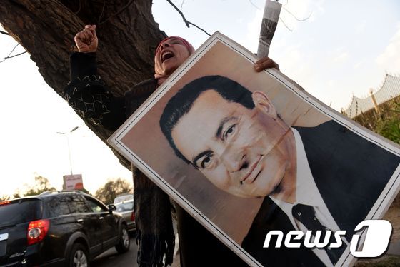 지난 2일(현지시간) 카이로 마디 군병원 밖에서 호스니 무바라크 전 이집트 대통령 지지자들이 무바라크의 사진을 들고 지지 구호를 외치고 있다. 2011년 초 '아랍의 봄'으로 촉발된 대규모 반정부 시위를 유혈 진압한 혐의로 기소된 무바라크 전 대통령은 6년 재판 끝에 무죄판결을 받았다. © AFP=뉴스1 