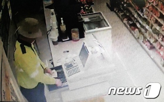 경찰 비옷을 입고 편의점 금고에서 돈을 훔치는  CCTV 영상 캡쳐.(순천경찰서 제공)/뉴스1 © News1 지정운 기자