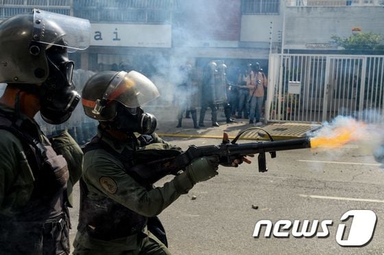 베네수엘라 국가수비대가 26일(현지시간) 수도 카르카스에서 반정부 시위대를 향해 발포하고 있다. © AFP=뉴스1