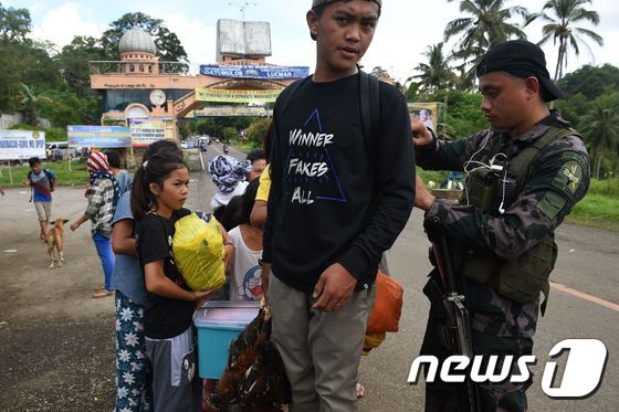 최근 계엄령이 선포된 필리핀 남부 말라위 지역에서 수십만명의 주민들이 피난길에 올랐다. 이곳에 투입된 병력들은 떠나는 주민들의 짐을 수색하고 있다. © AFP=뉴스1