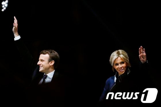 7일(현지시간) 에마뉘엘 마크롱 프랑스 대통령 당선인과 부인 브리짓 여사가 프랑스 파리 루브르박물관 앞에서 지지자들에게 인사하고 있다. © AFP=뉴스1