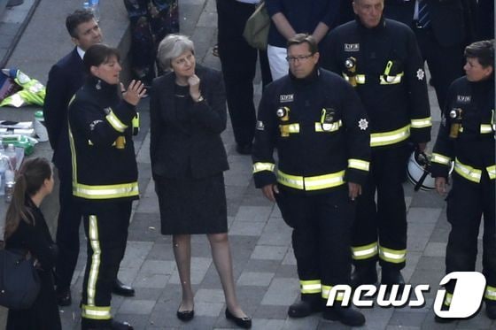 14일(현지시간) 영국 런던 그렌펠타워 화재 참사 현장을 방문한 테레사 메이 총리가 런던 소방청 직원의 설명을 듣고 있다. © AFP=뉴스1