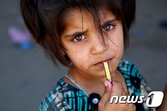 27일(현지시간) 시리아 라카에서 피난길에 오른 한 소녀가 손에 탄피를 들고 있다. © AFP=뉴스1