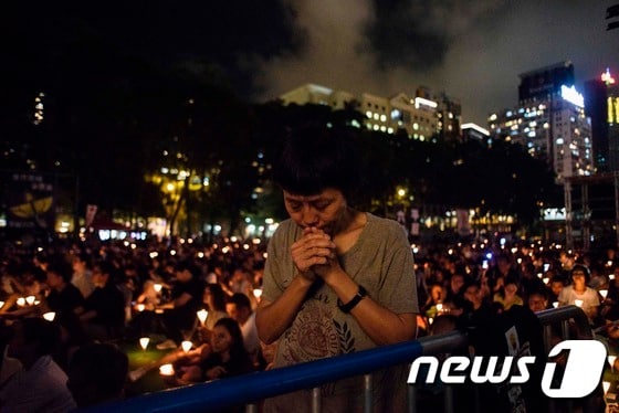 지난해  천안문 사태 28주년을 맞아 홍콩의 빅토리아 공원에서 한 여성이 희생자를 추모하는 철야 촛불집회에서 기도를 하고 있다.  © AFP=뉴스1 © News1 