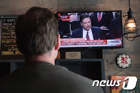 미국 일리노이주 시카고의 한 식당에서 한 남성이 제임스 코미 전 미 연방수사국(FBI) 국장이 출석한 상원 정보위원회 중계 방송을 시청하고 있다.  © AFP=뉴스1
