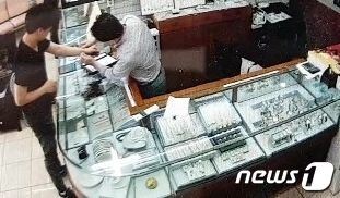 지난 8일 오전 10시 10분쯤 피의자가 금은방에 들어가 주인에게 금팔찌를 보여달라며 시착용을 하고 있다.(부산지방경찰청 제공)© News1
