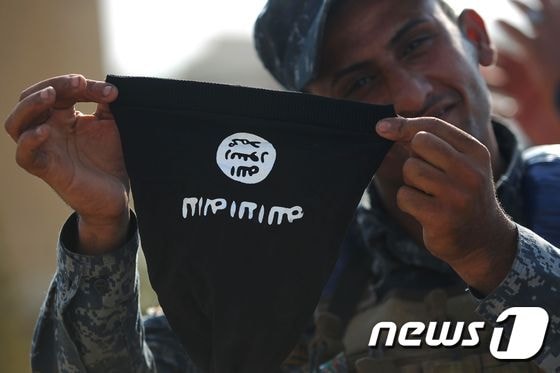 이라크 모술을 탈환한 연방경찰이 이슬람국가(IS) 국기 마스크를 들어보이고 있다. © AFP=뉴스1