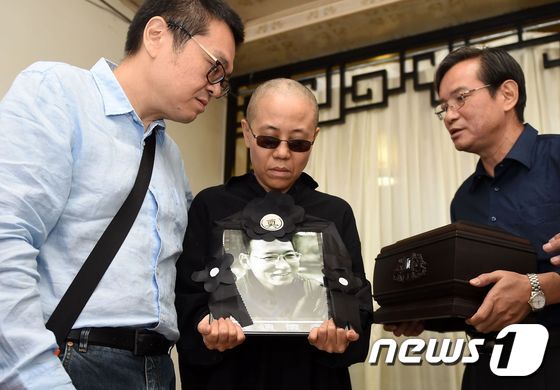 지난 13일 타계한 중국 반체제 인사 류샤오보의 부인 류샤(가운데)가 남편의 영정사진을 들고 애도하고 있다.  © AFP=뉴스1 © News1 정이나 기자