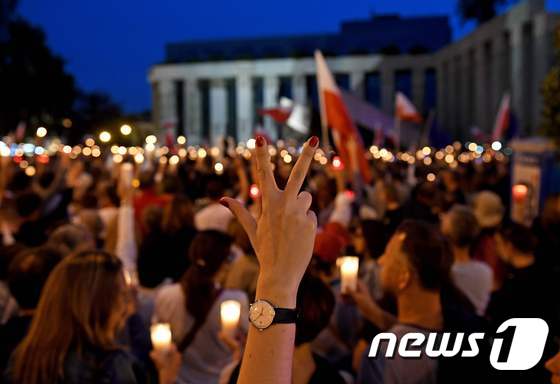 23일(현지시간) 폴란드 수도 바르샤바에서 시민들이 촛불과 국기를 들고 반정부 시위를 하고 있다. 시위대들은 정부 여당의 사법기관 장악을 위한 법개정에 반대하며 8일째 반정부 시위를 이어가고 있다. © AFP=뉴스1