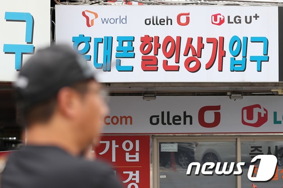 지난 16일 오후 서울 용산구의 한 핸드폰 판매업소 앞을 시민들이 지나고 있다.  © News1 임세영 기자