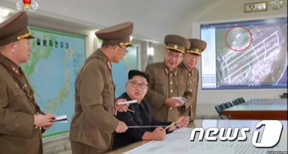 김정은 북한 노동당 위원장 왼편 화면에 괌 앤더슨 공군기지 위성사진이 보인다. 이 사진은 2011년 촬영된 것이라고 미국의 소리(VOA) 방송이 전했다. [출처=조선중앙TV, VOA]