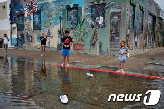 아이들이 텍사스 주 겔버스턴의 길거리에서 불어난 물 위에 장난감 배를 띄우고 있다. © AFP=뉴스1