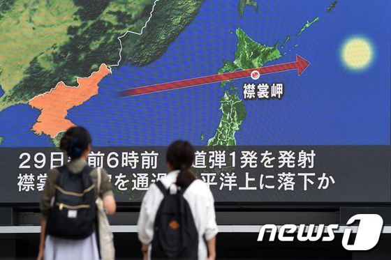 북한이 발사한 미사일이 일본 상공을 통과한 29일 도쿄 행인들이 뉴스 전광판에 시선을 두고 있다.© AFP=뉴스1