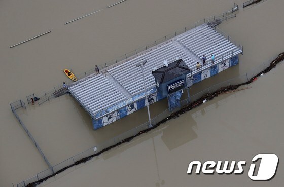홍수로 물에 잠긴 집 지붕 위에서 구조를 기다리는 사람들. © AFP=뉴스1
