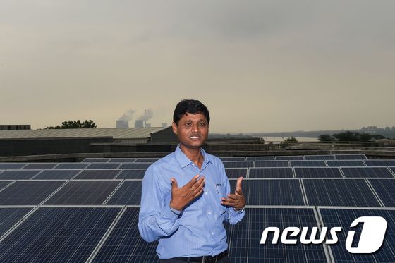 인도 서부 아마다바드주 인근  IT회사 빌딩 꼭대기에 설치된 태양광 패널 앞에서 인도델리공과대학 교수가 서 있다. © AFP=뉴스1