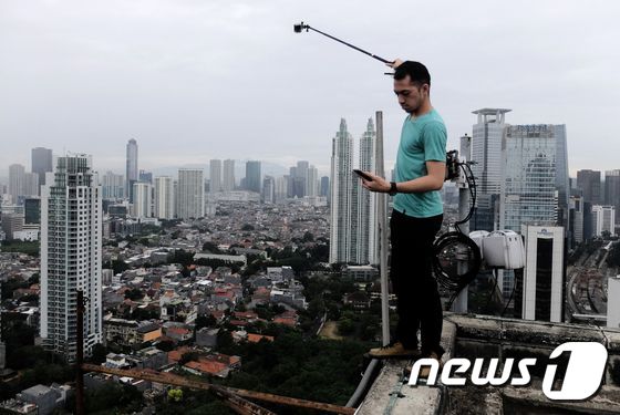 고층 건물에서 사진을 찍는 한 남성. (자료사진)© AFP=뉴스1