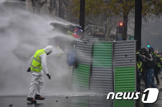 프랑스 노란조끼 시위 도중 경찰이 물대포를 사용하자 몸을 숨긴 시위 참가자들 © AFP=뉴스1