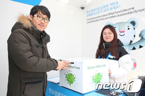 평창동계올림픽 친환경 홍보관(PyeongChang 2018 Green Pavilion)’에서 한 관람객이 탄소상쇄기금 모금함에 기금을 기부하고 있다. (한국환경산업기술원 제공) © News1