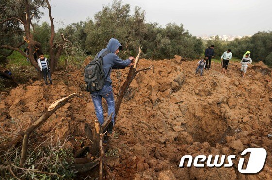 <br />이스라엘군 공습이 떨어진 장소를 살피는 가자지구 팔레스타인인들. © AFP=뉴스1