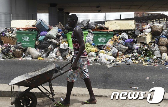 27일(현지시간) 나이지리아 라고스 주에서 한 남성이 쓰레기더미 옆을 지나가고 있다. © AFP=뉴스1