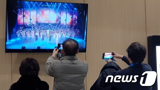북한 예술단의 공연에 들어가지 못한 시민들이 공연장 로비에서 공연이 생중계되는 모니터를 촬영하고 있다. © News1 홍기삼 기자