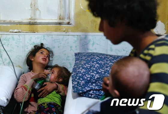 화학무기 추정 공격이 벌어진 시리아 두마에서 어린이들이 유아에게 산소 마스크를 씌우고 있다. <자료사진> © AFP=뉴스1