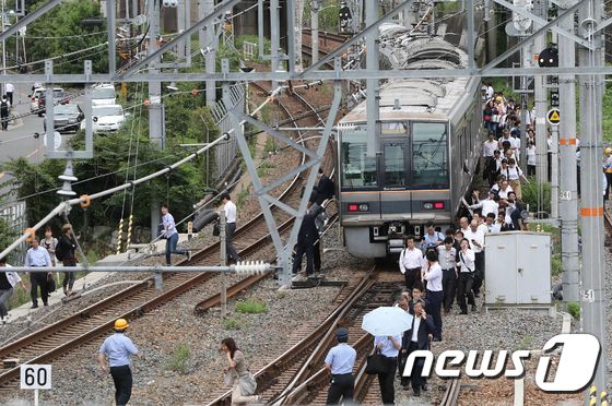 18일(현지시간) 일본 오사카 부근에서 진도 5.9의 지진으로 열차가 운행을 멈추자 승객들이 철로를 따라 걸어가고 있다. © AFP=뉴스1 © News1 우동명 기자