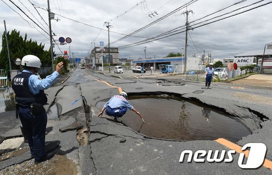 18일(현지시간) 일본 오사카 부근에서 진도 5.9의 지진 발생해 다카쓰키의 푹 꺼진 도로에 물이 고여있는 모습이 보인다. © AFP=뉴스1 © News1 우동명 기자