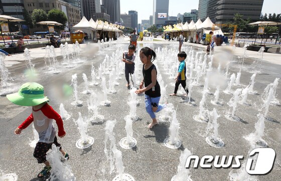서울의 낮 최고기온이 36도를 기록하는 등 연일 폭염이 이어지고 있는 21일 오후 서울 광화문광장 분수대를 찾은 아이들이 물놀이를 하며 더위를 식히고 있다. 2018.7.21/뉴스1 © News1 구윤성 기자