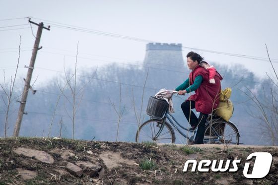 아이를 업고 자전거를 타는 북한 주민의 모습 <자료사진> © AFP=뉴스1