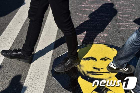 지난해 7월 모스크바에서 열린 블라디미르 푸틴 러시아 대통령에 대한 반대 시위에서 시위대원들이 푸틴 대통령의 사진을 밟고 있다. <자료사진> © AFP=뉴스1 © News1 강민경 기자
