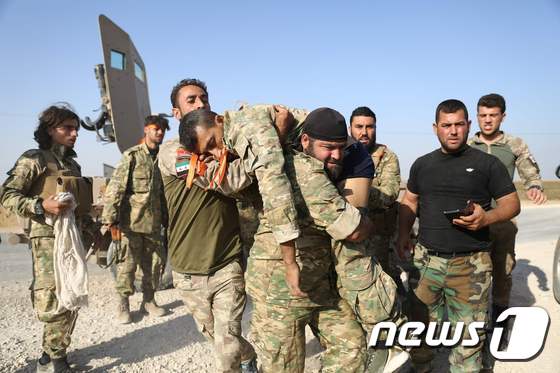 터키의 지원을 받는 시리아 반군이 13일 라스알아인 지역에서 부상당한 군인을 나르고 있다. © AFP=뉴스1