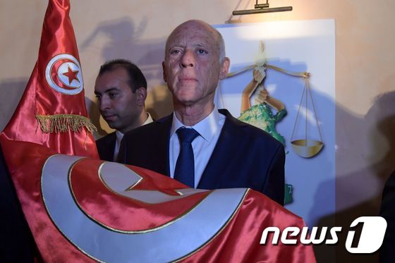 카이스 사이에드 튀니지 대통령 후보가 13일 지지자들 앞에서 튀니지 국기를 꺼내들고 있다. © AFP=뉴스1