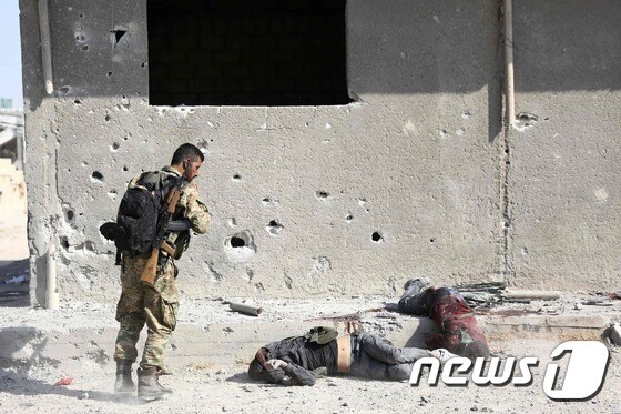 17일(현지시간) 시리아 국경 라스 알 아인에서 쿠르드 민병대(YPG) 시체를 바라보고 있는 시리아 군인. © AFP=뉴스1